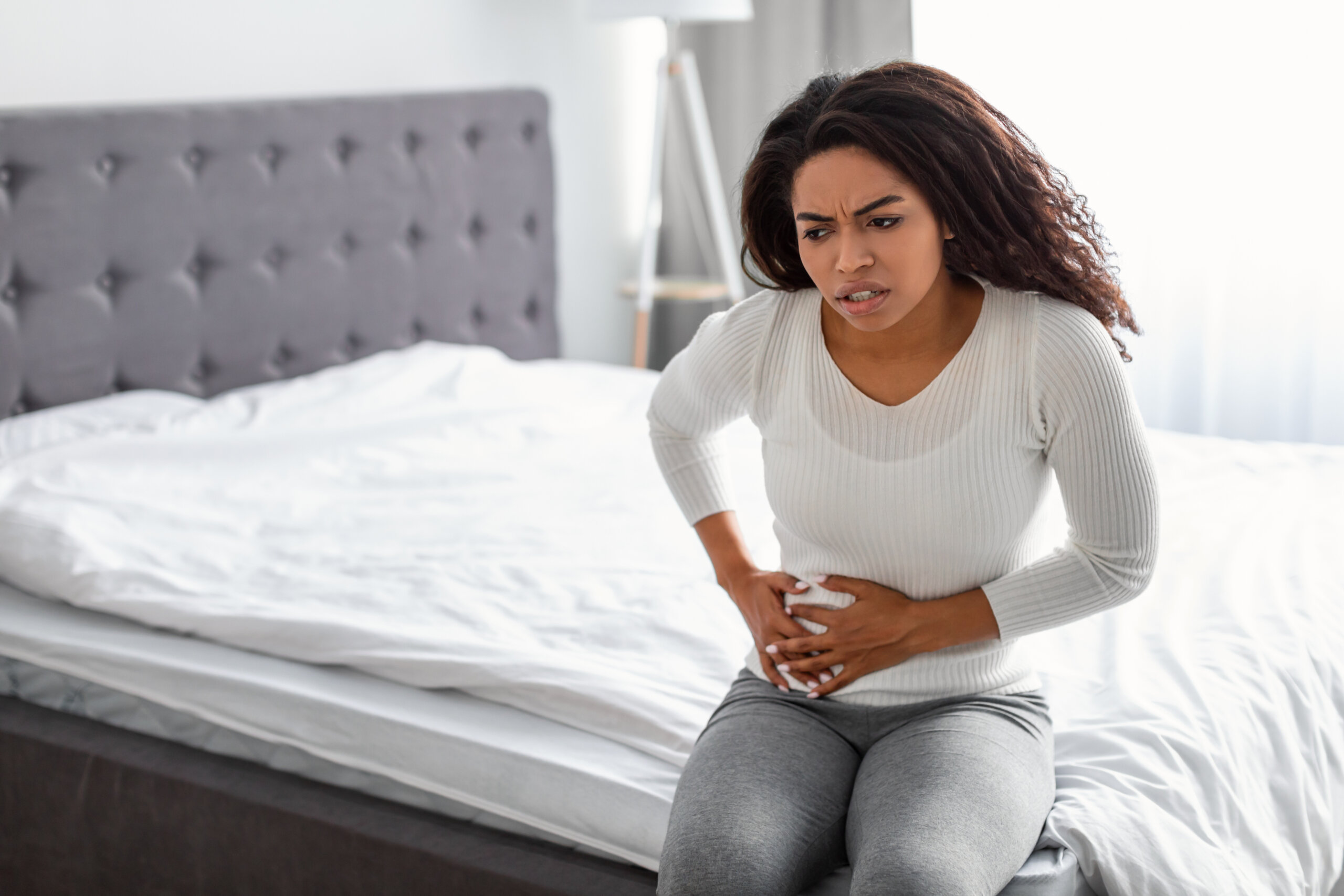 woman on edge of bed with abdominal pain in her right side.