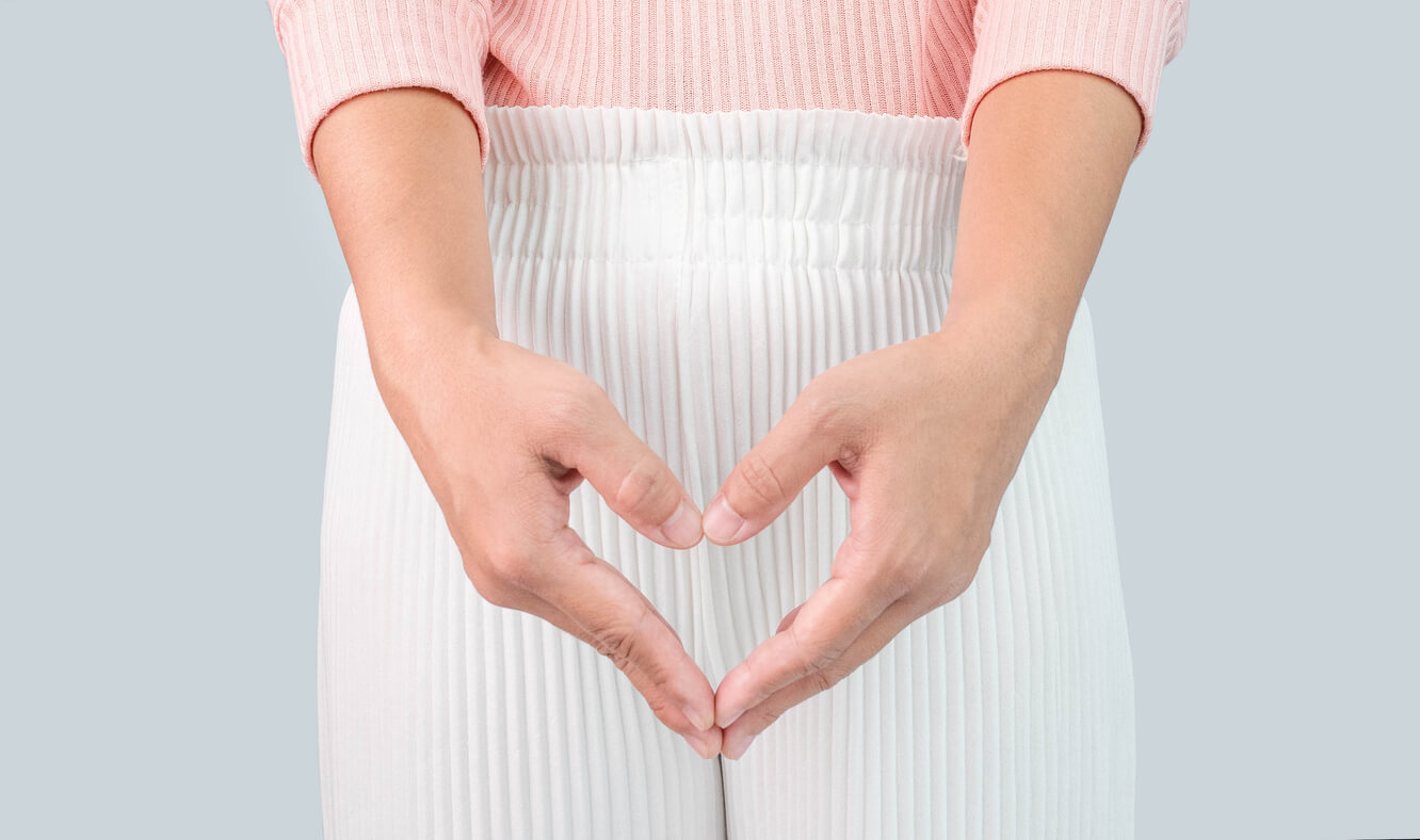 Close up view of young woman and Hand is a symbol of heart over her crotch, conveying curiosity about what vaginal discharge may mean.